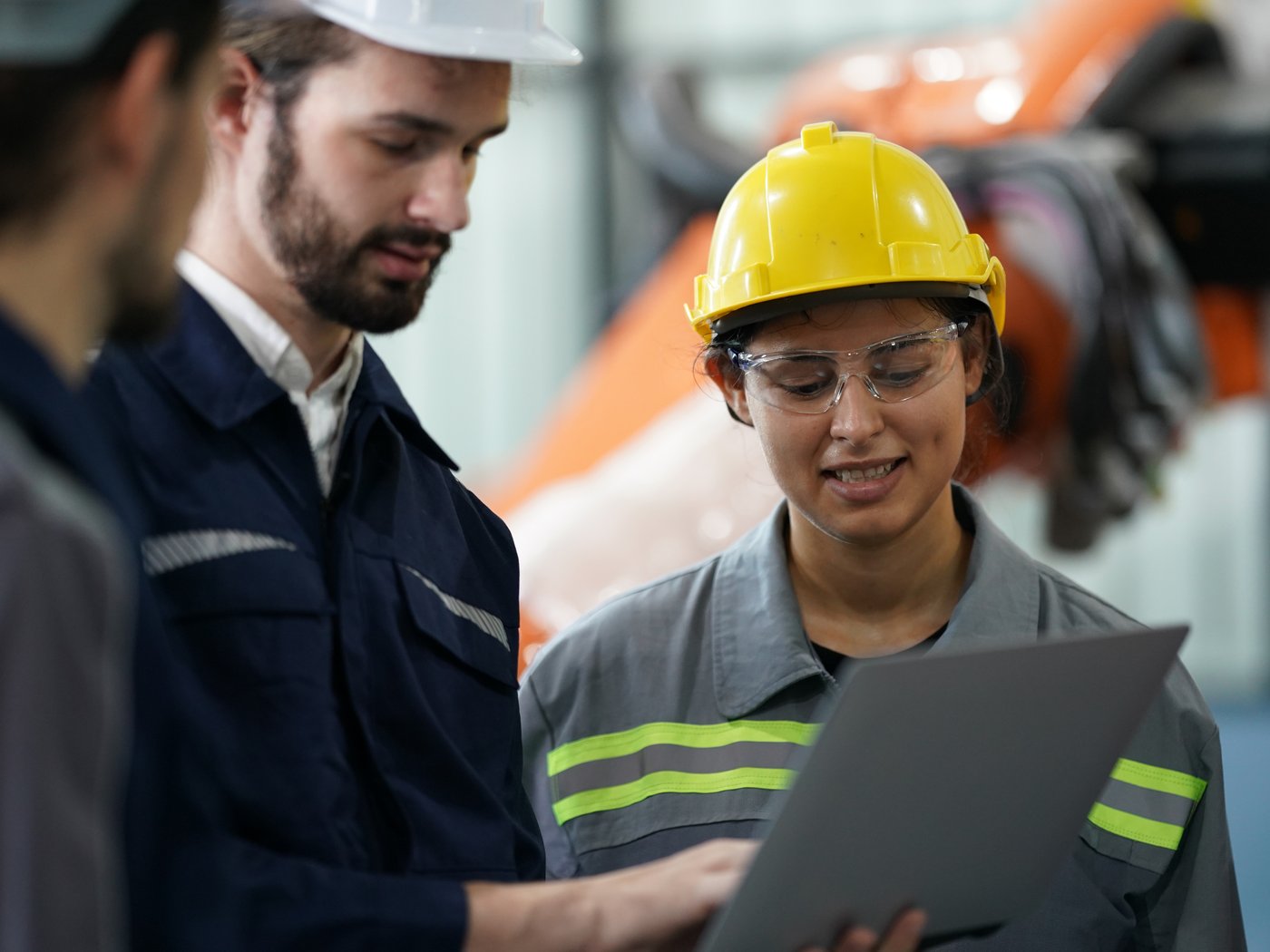 Equipe técnica revisando dados de manutenção junto a um robô industrial